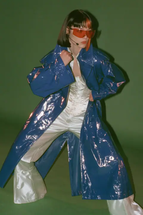 Y2K high fashion editorial, a 2001 couture magazine story: full-length shot, head to toe with the feet in frame, of a young Caucasian American woman with pale skin and a glossy black blunt bob with heavy straight…
