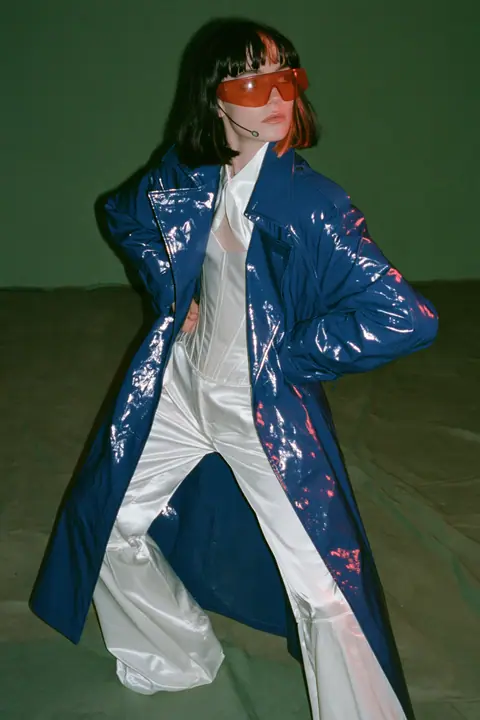 Y2K high fashion editorial, a 2001 couture magazine story: full-length shot, head to toe with the feet in frame, of a young Caucasian American woman with pale skin and a glossy black blunt bob with heavy straight…