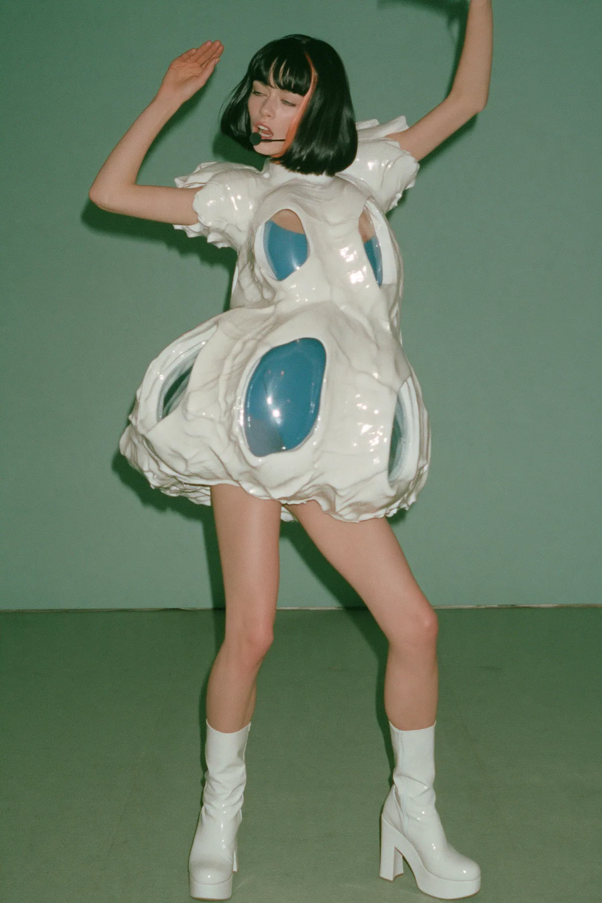 Y2K high fashion editorial, a 2001 couture magazine story: full-length shot, head to toe with the feet in frame, of a young Caucasian American woman with pale skin and a glossy black blunt bob with heavy straight…