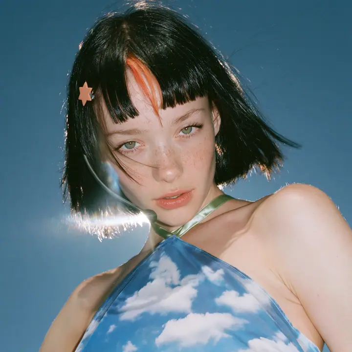 Y2K high fashion editorial, a 2001 couture magazine story: a square album cover photograph of a Caucasian American woman in her mid-twenties with pale skin and light freckles, a glossy black blunt jaw-length bob with…