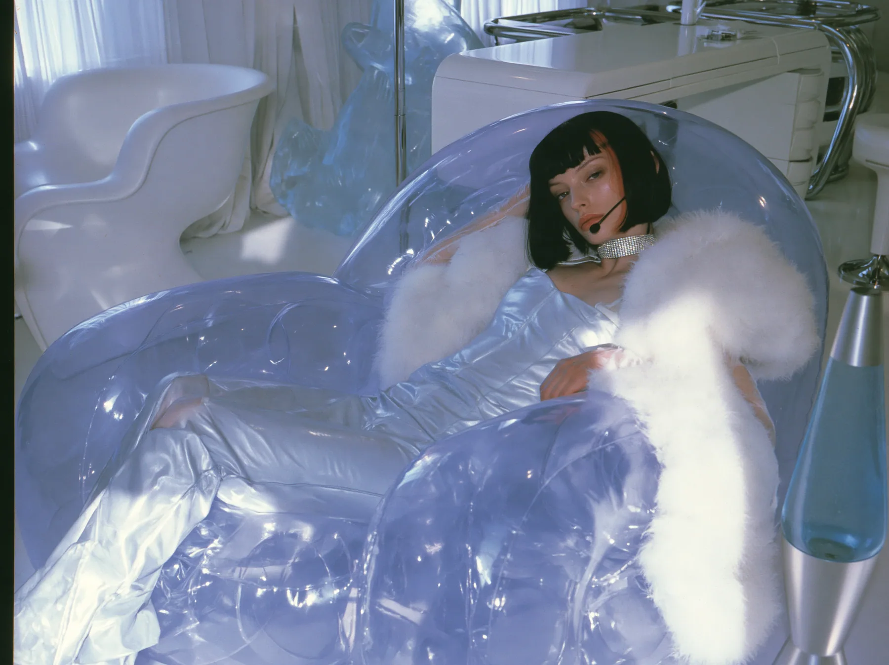 Y2K high fashion editorial, a 2001 couture magazine story: a young Caucasian American woman with pale skin and a glossy black blunt bob with heavy straight bangs and one clay-orange streak, a thin black headset…