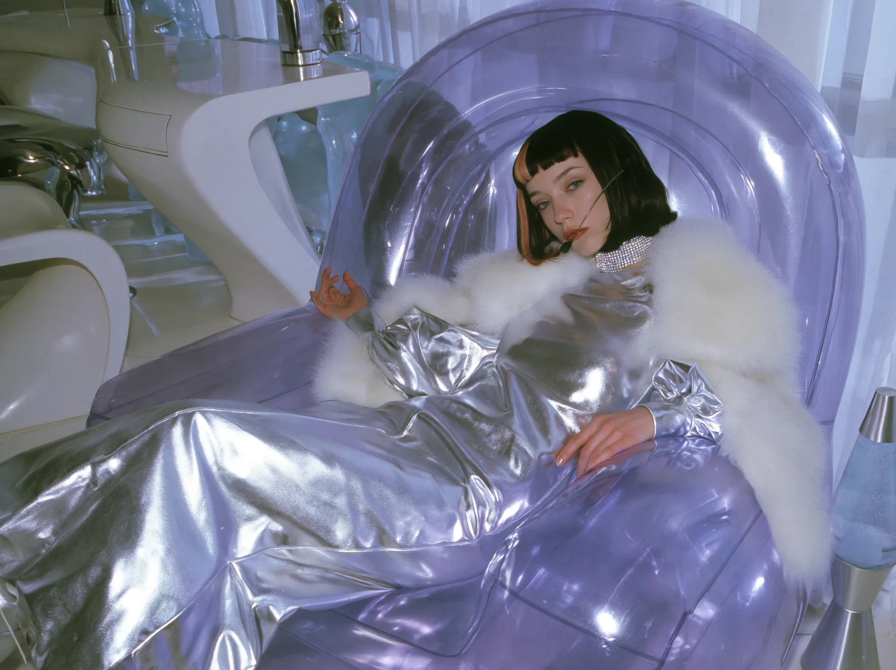 Y2K high fashion editorial, a 2001 couture magazine story: a young Caucasian American woman with pale skin and a glossy black blunt bob with heavy straight bangs and one clay-orange streak, a thin black headset…