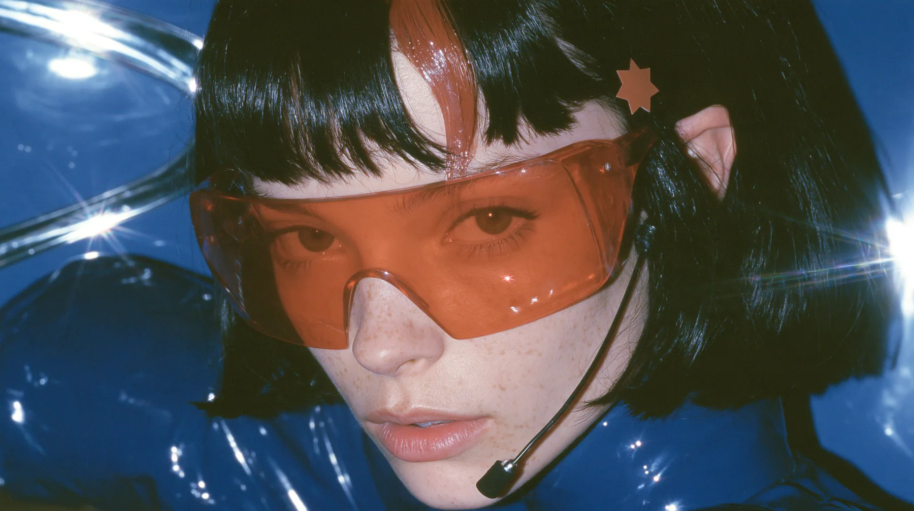 Y2K high fashion editorial, a 2001 couture magazine story: a Caucasian American woman in her mid-twenties with pale skin and light freckles, a glossy black blunt jaw-length bob with heavy straight bangs and one…